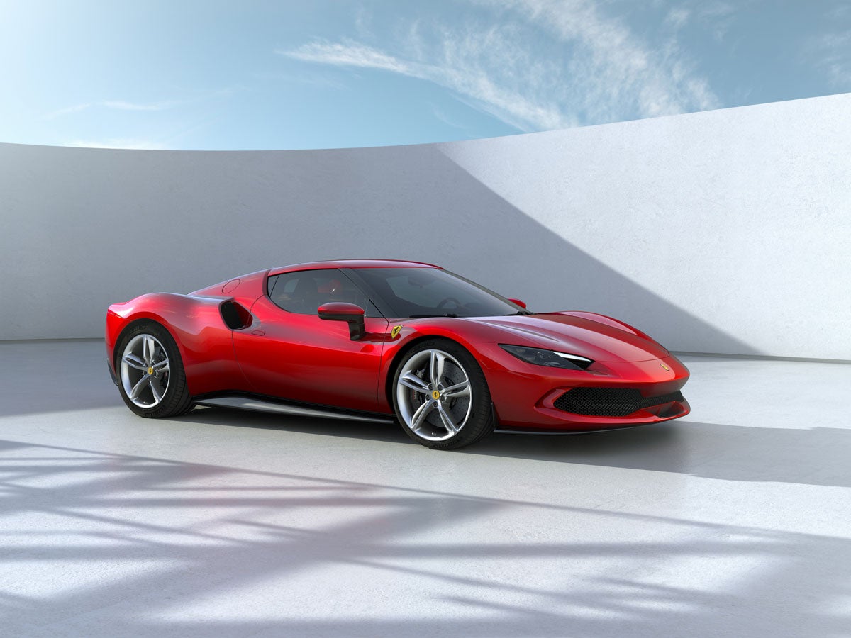 A red Ferrari 296 GTB in a modern, minimalist setting with a white curved wall and blue sky.