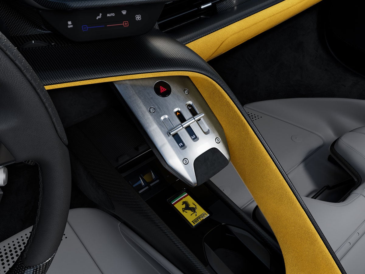 Close-up overhead view of a Ferrari's driver's side interior, showing the shifter and yellow trim.