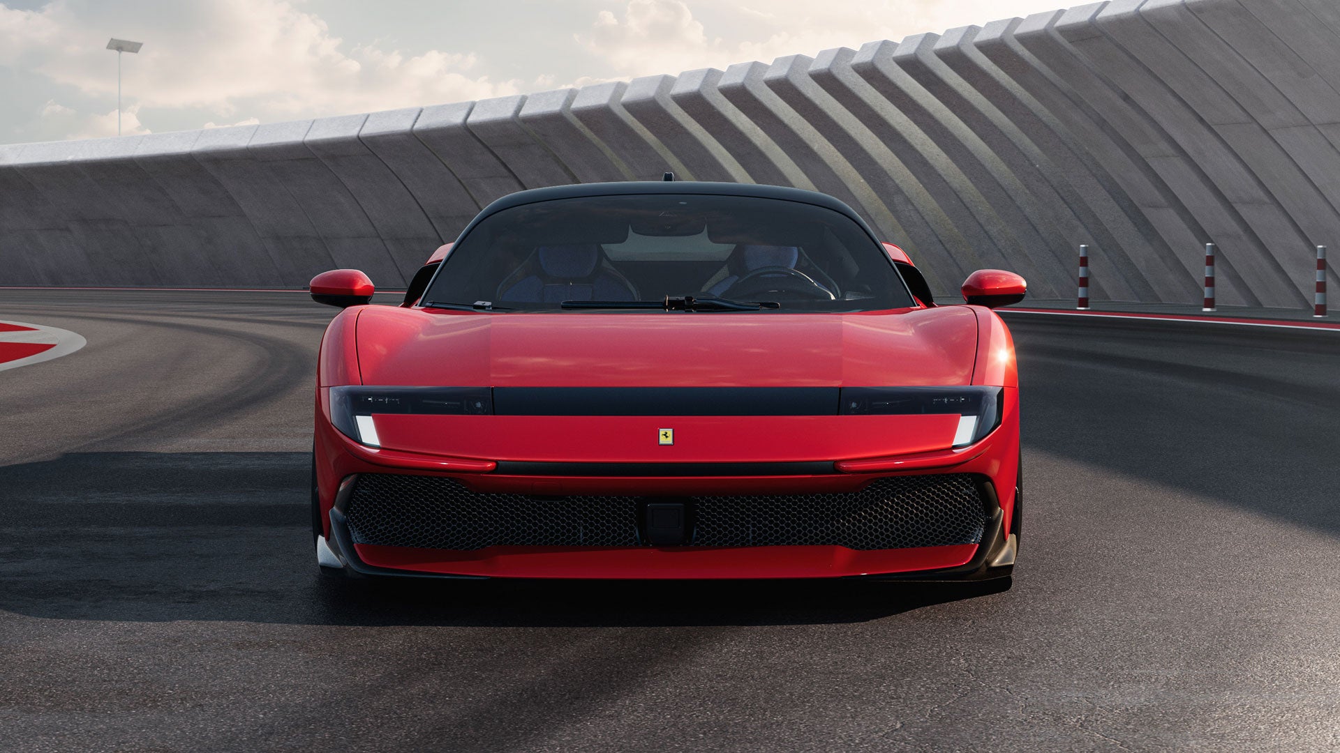 Front view of a sleek red Ferrari on a racetrack, with a textured concrete wall in the background.