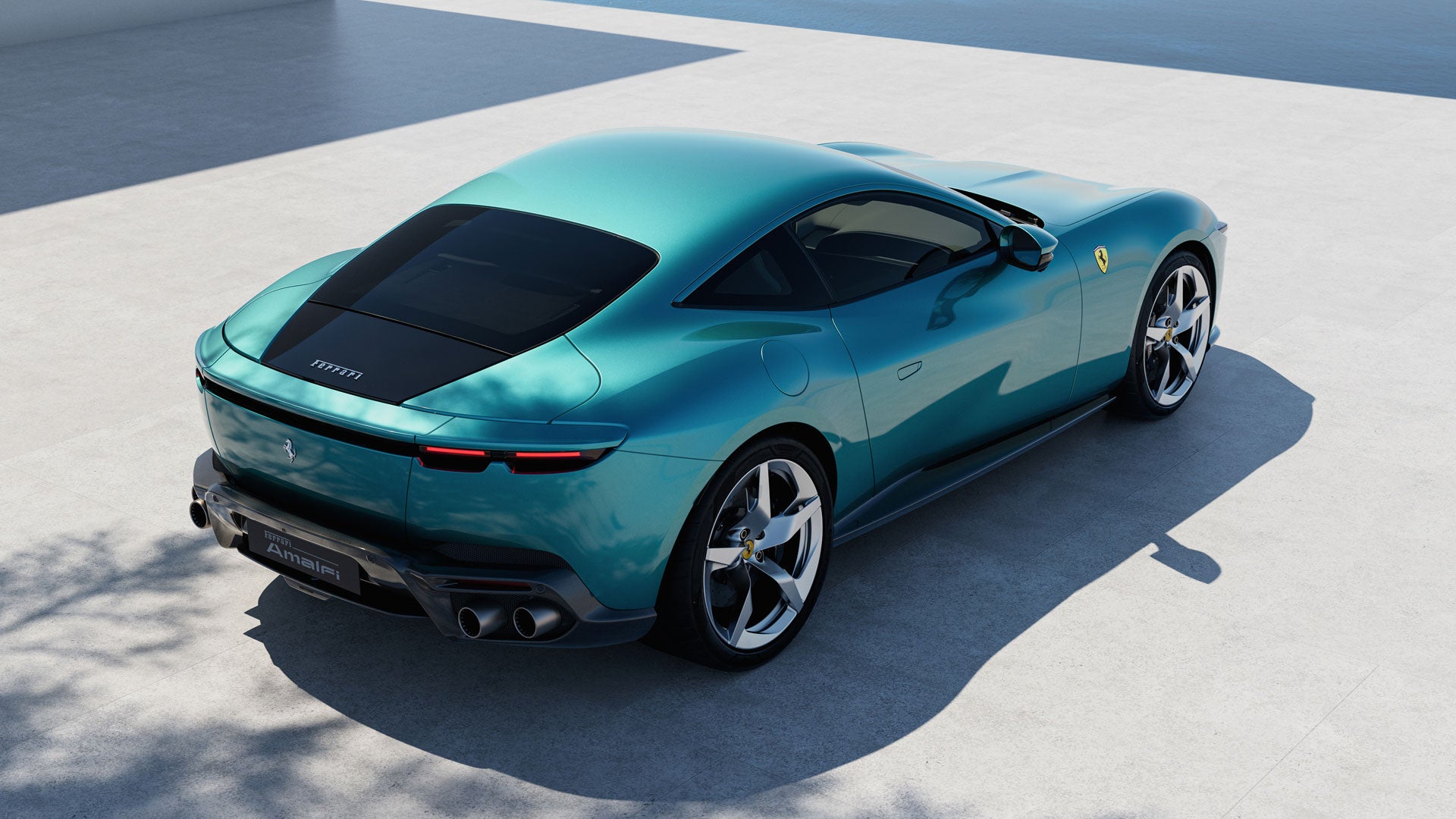 A teal Ferrari parked on a concrete surface, viewed from a high angle at the rear.