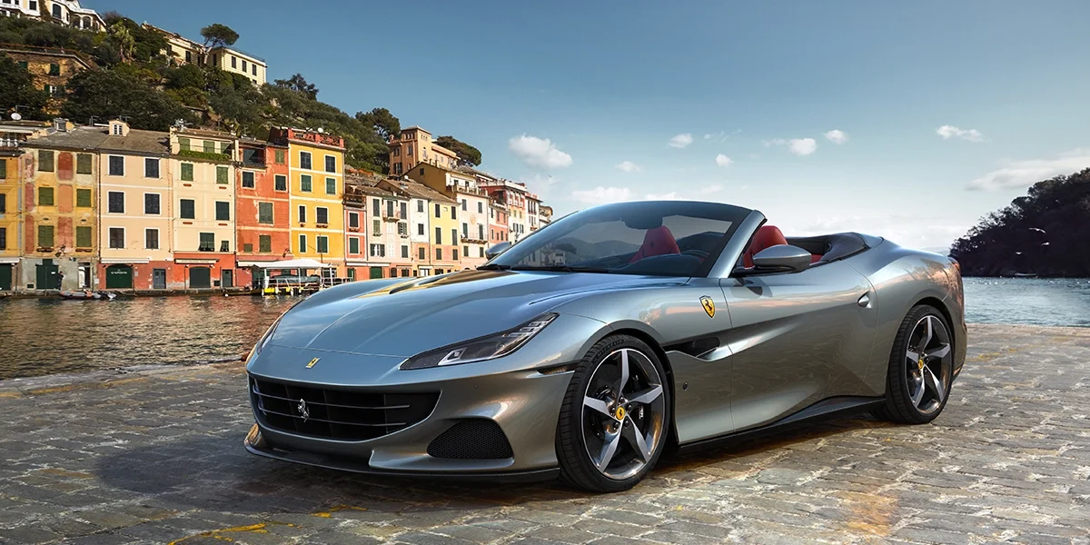 Ferrari Portofino M side profile near city waterfront skyline