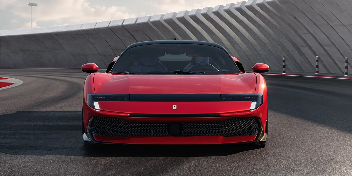 Front view of the Ferrari 849 Testarossa in red on a racetrack, showcasing its sleek headlights and aggressive grille design.
